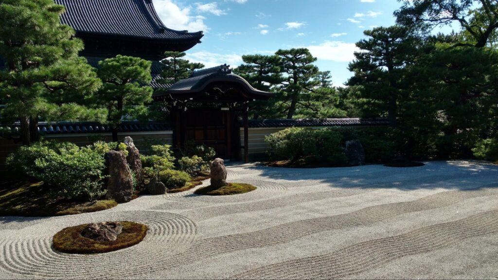 Classic raked karesansui zen garden with white sand raked in circular wave patterns around stones
